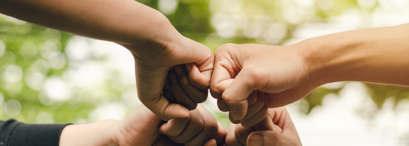 Vier aneinander gehaltene Fäuste für die Zusammenarbeit im Leitenden Kreis