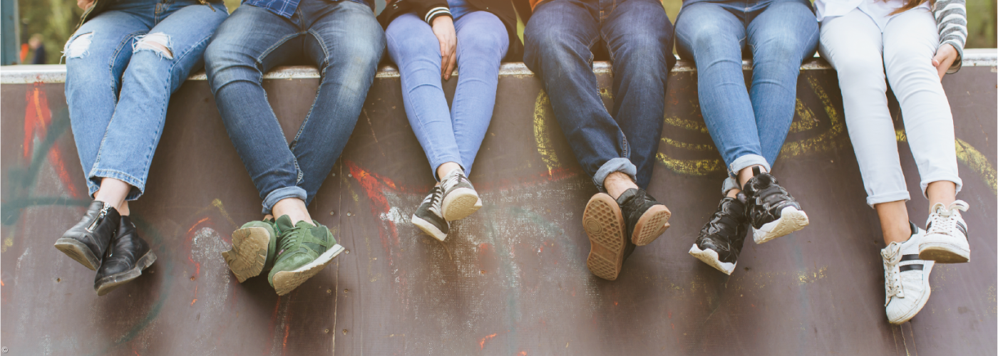 Beine von Personen, die auf einer Mauer sitzen.